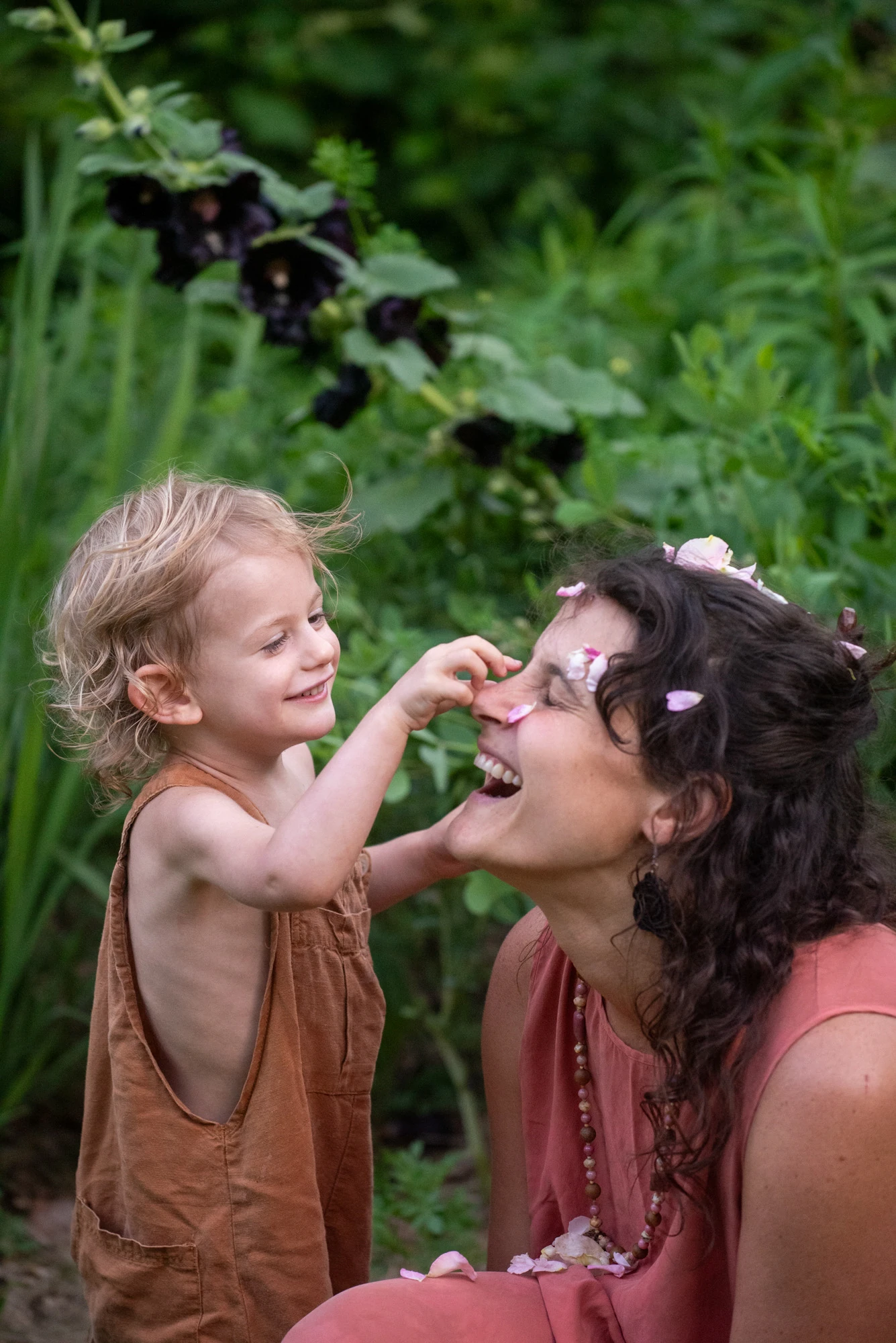 Mother and child sharing a tender laugh in the lush green Asheville light